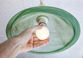 Human hand twists LED lamp into ceiling fixture green glass. Royalty Free Stock Photo
