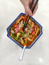 Human hand uses chopsticks taking chinese nodlles from the bowl top view Royalty Free Stock Photo