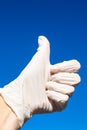 Human hand in white medical latex glove holding light azur medical mask on intense blue background. horizontal composition with co