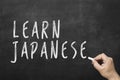 Human hand writing text on blackboard: Learn japanese