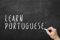 Human hand writing text on blackboard: Learn portuguese