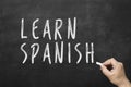 Human hand writing text on blackboard: Learn spanish