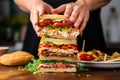 human hands adding layers to a triple-decker sandwich