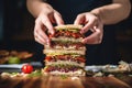 human hands adding layers to a triple-decker sandwich