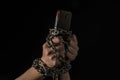 Human hands chained with a smartphone on a black background Royalty Free Stock Photo