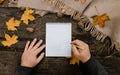 Human hands with a cup of coffee and scarf at wooden table with notebook and pen and autumn leaves. Human hands with a cup of Royalty Free Stock Photo