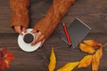 Human hands with a cup of espresso at a wooden table with notebook and pen and autumn leaves Royalty Free Stock Photo