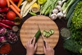 Human hands cutting cucumber and variation of vegetables and spices around Royalty Free Stock Photo