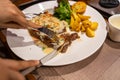 Human hands using knife and fork cutting delicious sirloin steak