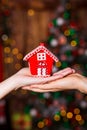 Human hands holding decorative red house against blurred background. Christmas and home comfort concept. Royalty Free Stock Photo