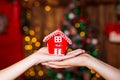 Human hands holding decorative red house against blurred background. Christmas and home comfort concept. Royalty Free Stock Photo