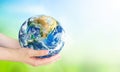 Human hands holding earth globe over blurred green and blue sky nature background. Elements of this image furnished by NASA Royalty Free Stock Photo