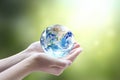 Human hands holding earth globe over blurred green nature background. Elements of this image furnished by NASA Royalty Free Stock Photo