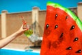 Human Hands Holding Glass. Coctail above watermelon float mattress by swimming pool on villa resort. Summer vacation. Luxury