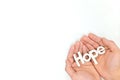 Human hands holding hope word cutout in white background. Top view with copy space. Royalty Free Stock Photo