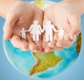 Human hands holding paper family over earth globe Royalty Free Stock Photo