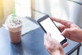 The human hands holding the smartphone and touch on mobile screen at coffee shop