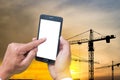 The human hands holding the smartphone and touch on mobile screen with silhouette construction site Royalty Free Stock Photo