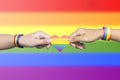 Human hands with LGBT rainbow flag wristband holding a rainbow heart