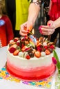 Human hands lighting candles on a chocolate fruit cake at a celebration