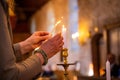 Human hands lighting a holy candle in a church