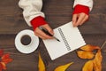 Human hands with pen and notebook at wooden table with cup of coffee and autumn leaves Royalty Free Stock Photo