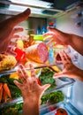 Human hands reaching for food at night in the open refrigerator