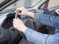 Human hands on steering wheel, inside cab view, close up, selective focus. Ordinary man driving a car.