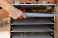 Human hands, taking out empty metal pan from dehydrating machine. Equipment for producing dry meat or vegetarian jerkies.