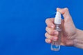 Human hands use spray, disinfectant, antiseptic in bubble, jar on blue background