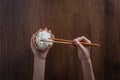 Human hands are using chopsticks to grab jasmine rice cooked from a wooden bowl. over wooden background. Thai Jasmine rice Royalty Free Stock Photo