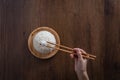 Human hands are using chopsticks to grab jasmine rice cooked from a wooden dish. over wooden background. Thai Jasmine rice Royalty Free Stock Photo