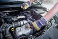 Human hands with wrenches in protective gloves upon car engine