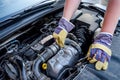 Human hands with wrenches in protective gloves upon car engine