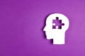 Human head paper silhouette with a puzzle piece cut out on the purple background. Mental health symbol Royalty Free Stock Photo