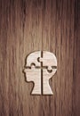 Human head silhouette with a jigsaw piece cut out on the wooden background, mental health concept. Royalty Free Stock Photo