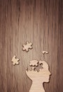 Human head silhouette with a jigsaw piece cut out on the wooden background, mental health concept. Royalty Free Stock Photo