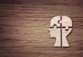 Human head silhouette with a jigsaw piece cut out on the wooden background, mental health concept Royalty Free Stock Photo