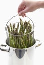 Human holding cooking pot with green asparagus