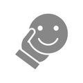 Human holding happy emoji gray icon. Share a good mood, emotions of satisfaction symbol