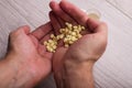 Human holds a handful of yellow small pills in his hands