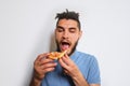 Human holds piece of cheese pizza with tomatoes in his hands and enjoys eating. Young cute Caucasian man with beard and dreadlocks Royalty Free Stock Photo