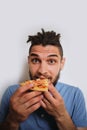 Human holds piece of cheese pizza with tomatoes in his hands and enjoys eating. Young cute Caucasian man with beard and dreadlocks Royalty Free Stock Photo