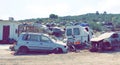 Discarded cars and trucks are piled up in a scrap heap outside. Toned Photo