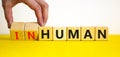 Human or inhuman symbol. Businessman turns wooden cubes and changes the word inhuman to human. Beautiful yellow table white Royalty Free Stock Photo