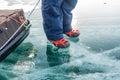 Human legs in hiking boot in ice crampons on the texture Baikal ice Royalty Free Stock Photo