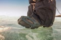 Human legs in hiking boot in ice crampons on the texture Baikal Royalty Free Stock Photo