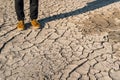 Human legs in sneakers and jeans standing on dried cracked earth Royalty Free Stock Photo