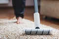 Human legs and a white turbo brush of a cordless vacuum cleaner cleans the carpet in the house Royalty Free Stock Photo