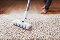 Human legs and a white turbo brush of a cordless vacuum cleaner cleans the carpet in the house Royalty Free Stock Photo